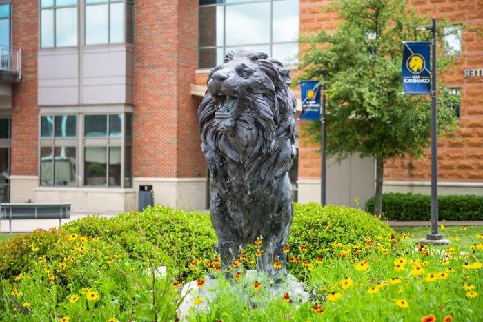 在A大学校园的基座上，一尊春花盛开的狮子雕像&M-Commerce.